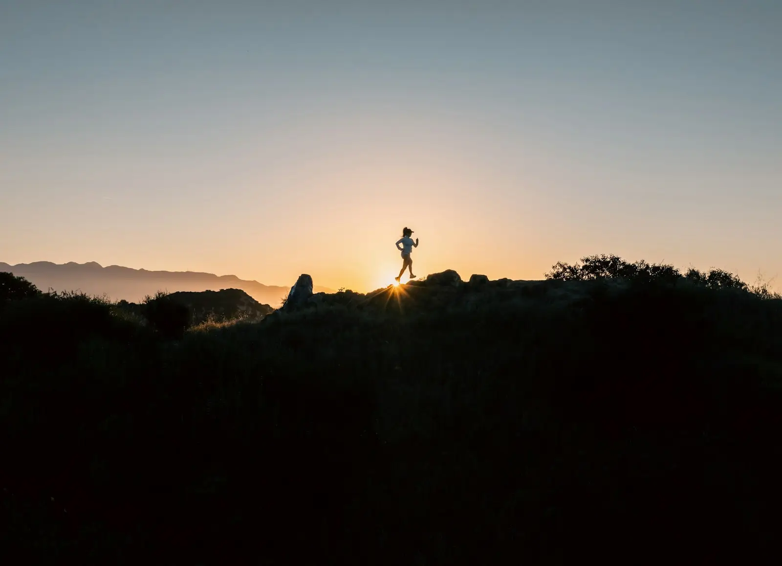 a person standing on top of a hill at sunset