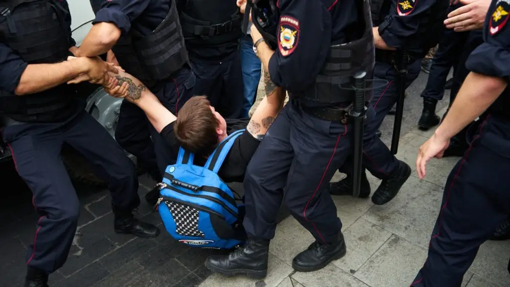 man in black jacket and black pants carrying blue and black backpack