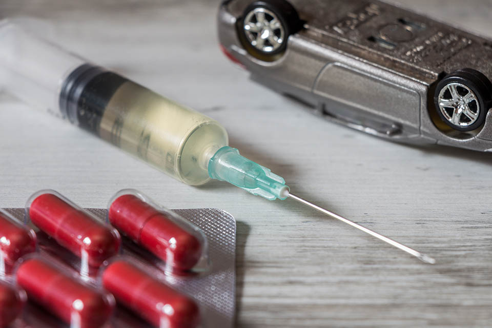 Driving under the influence of drugs. Pills, syringe and overturned car. Car accident concept