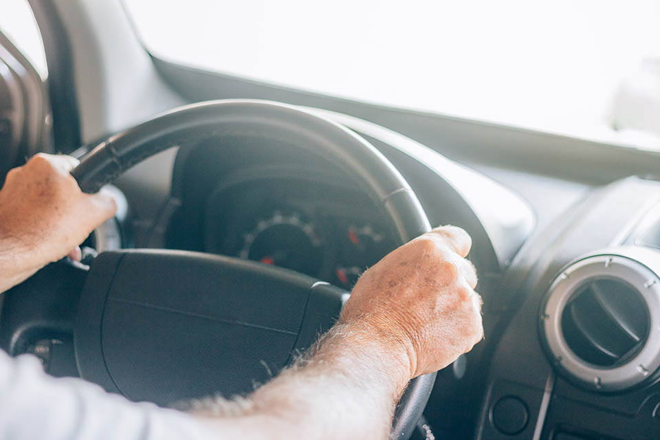 Man driving the car with both hands at the wheel. It has spots on the skin. Concept of defensive driving. Travel safely.