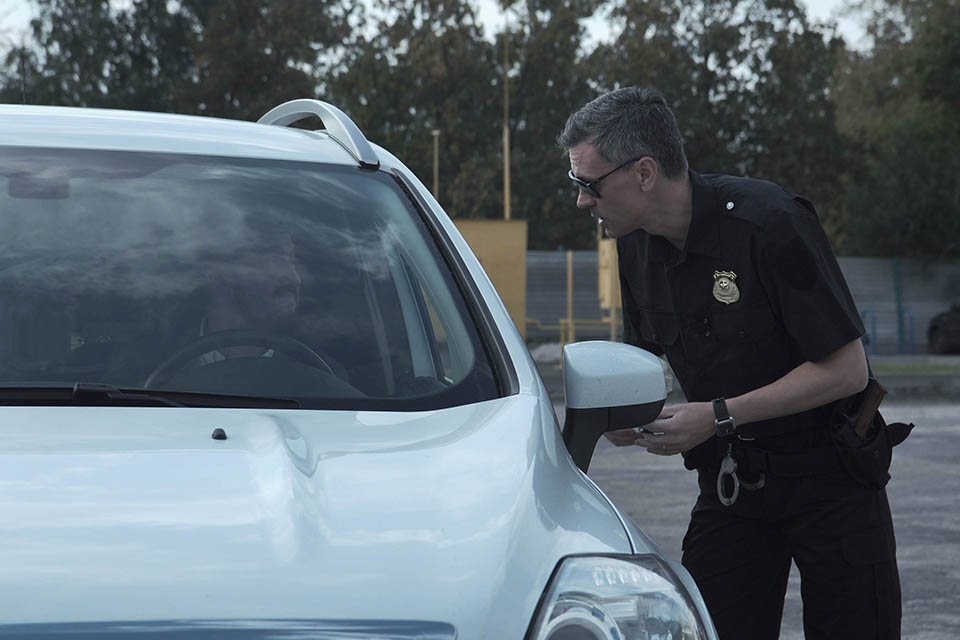 Police officer stopping the driver of a vehicle and questioning him over an alleged offence through the open window of the car